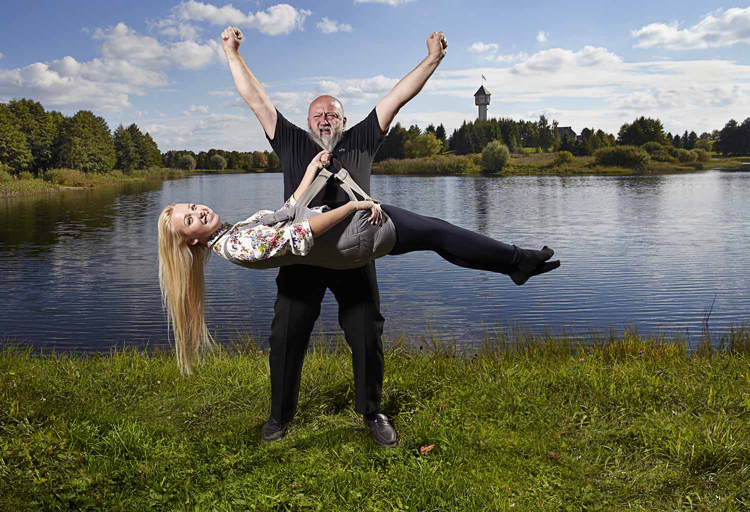 A woman in a harness is being lifted by a man’s beard, which is attached.