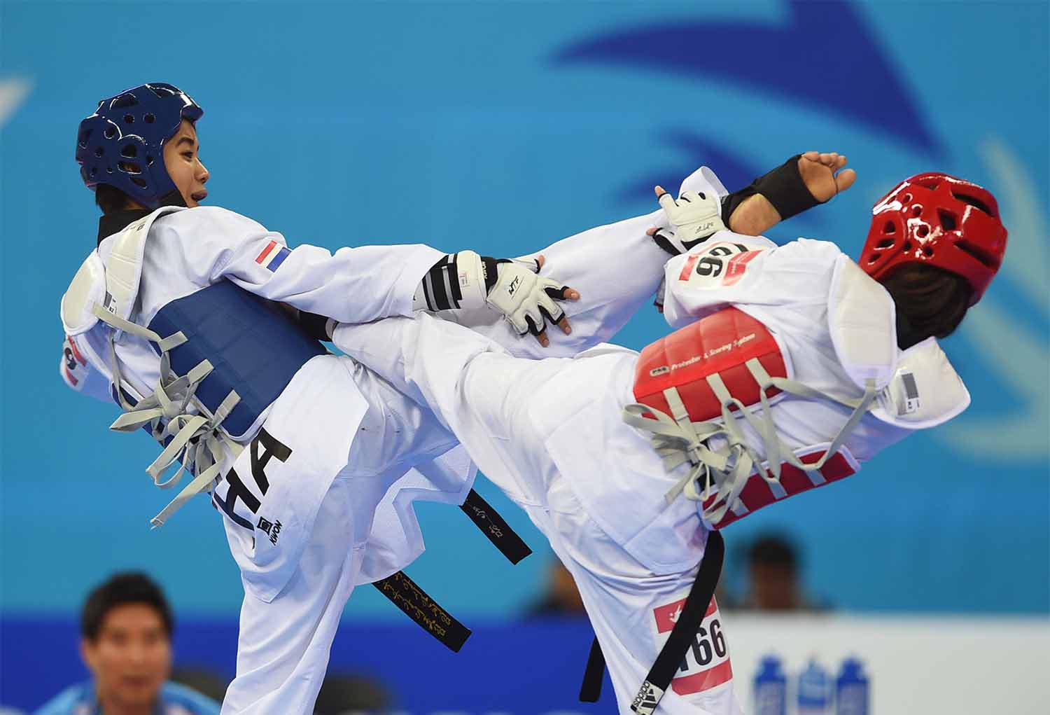 Two young women engage in a taekwondo fight.