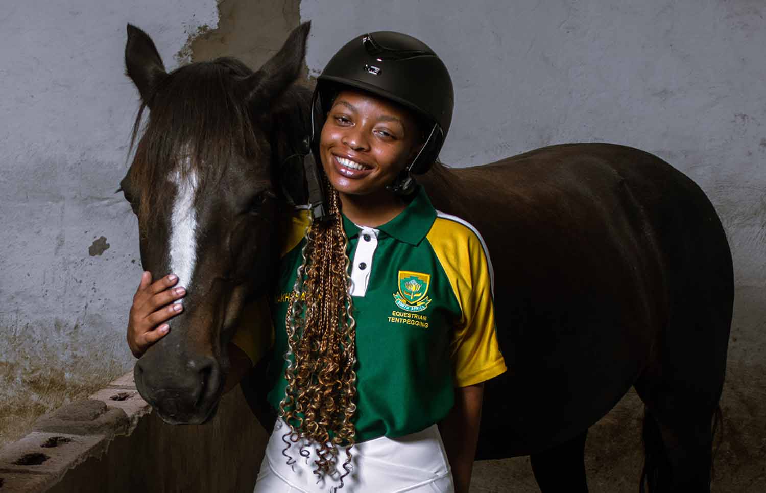 Khosi Dlomo poses with her arm around her horse.