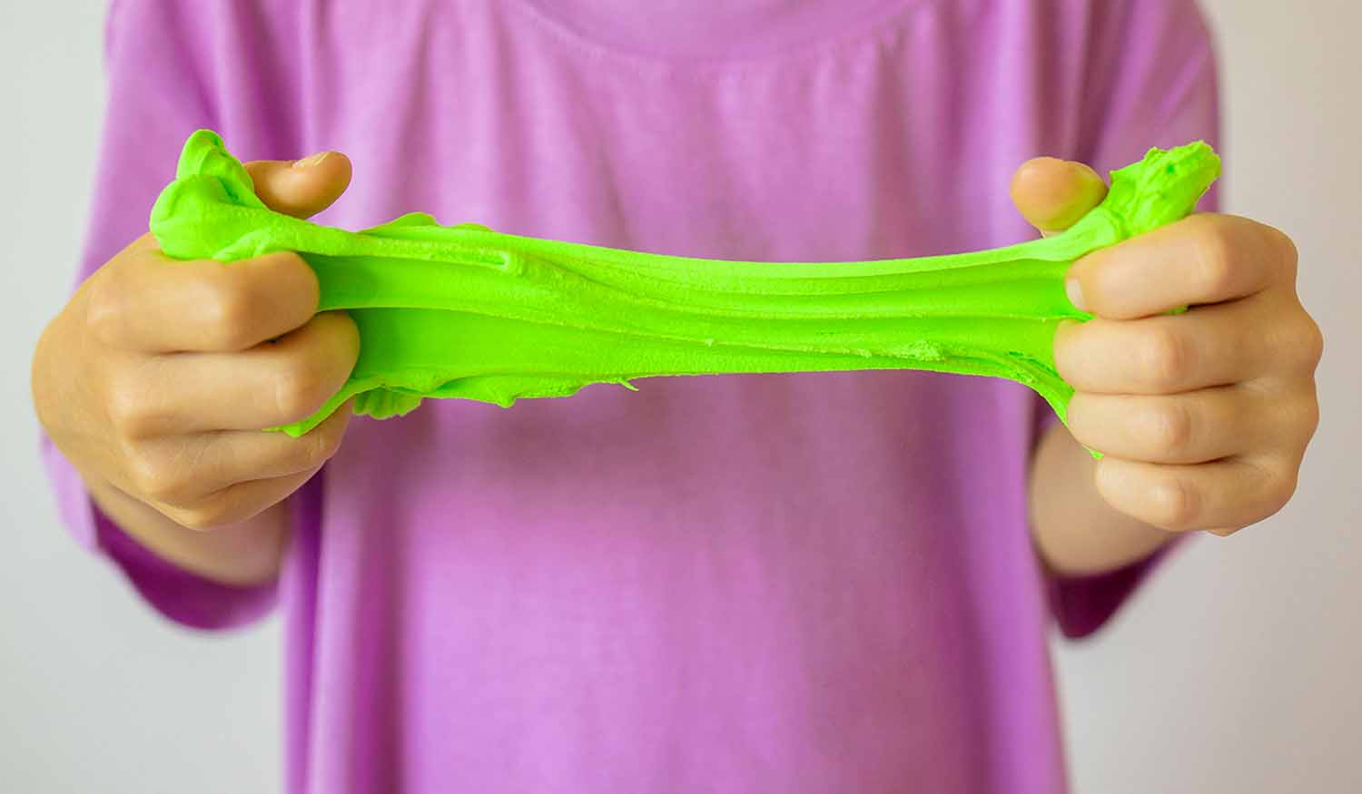 A child’s hands stretch some green slime.