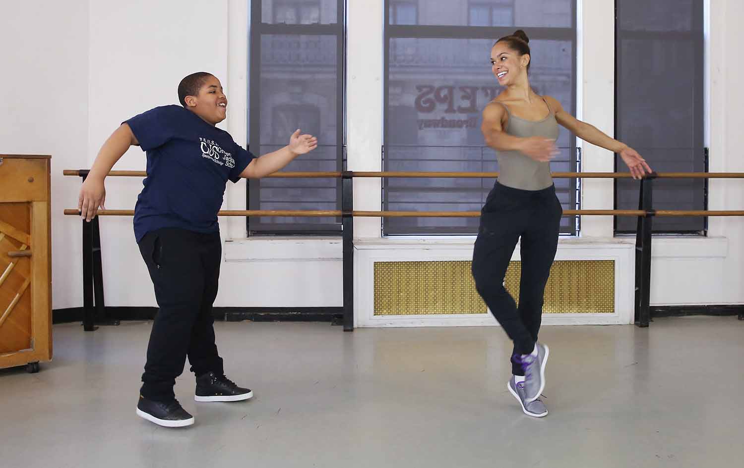 Misty Copeland and a teen boy dance together in a dance studio.