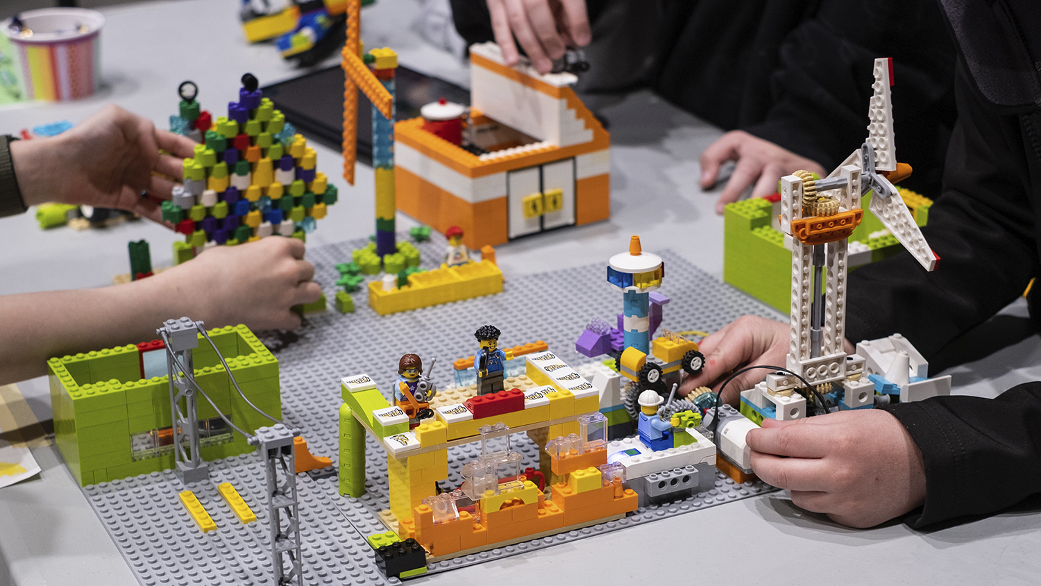 Hands are shown manipulating several pieces that have been constructed with wires and LEGO bricks.