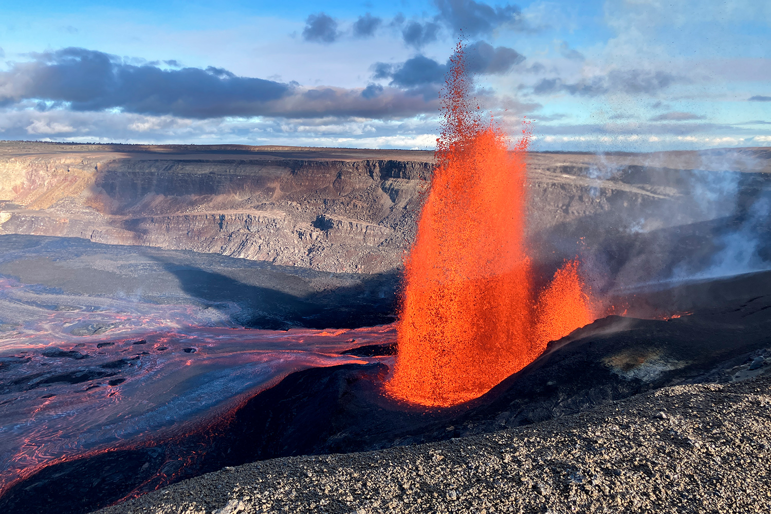 Lava spews into the air as a wide shot of a crater is shown.