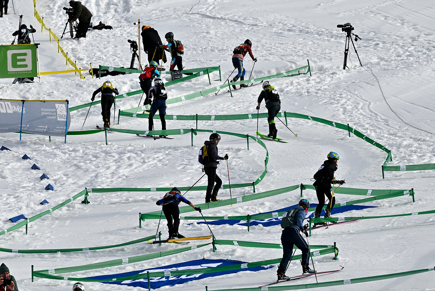 Skiers move along a marked trail that is climbing a mountain.