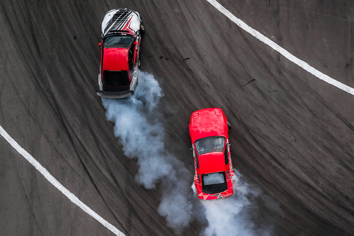 Part of a race track is in view with two race cars in motion on it.