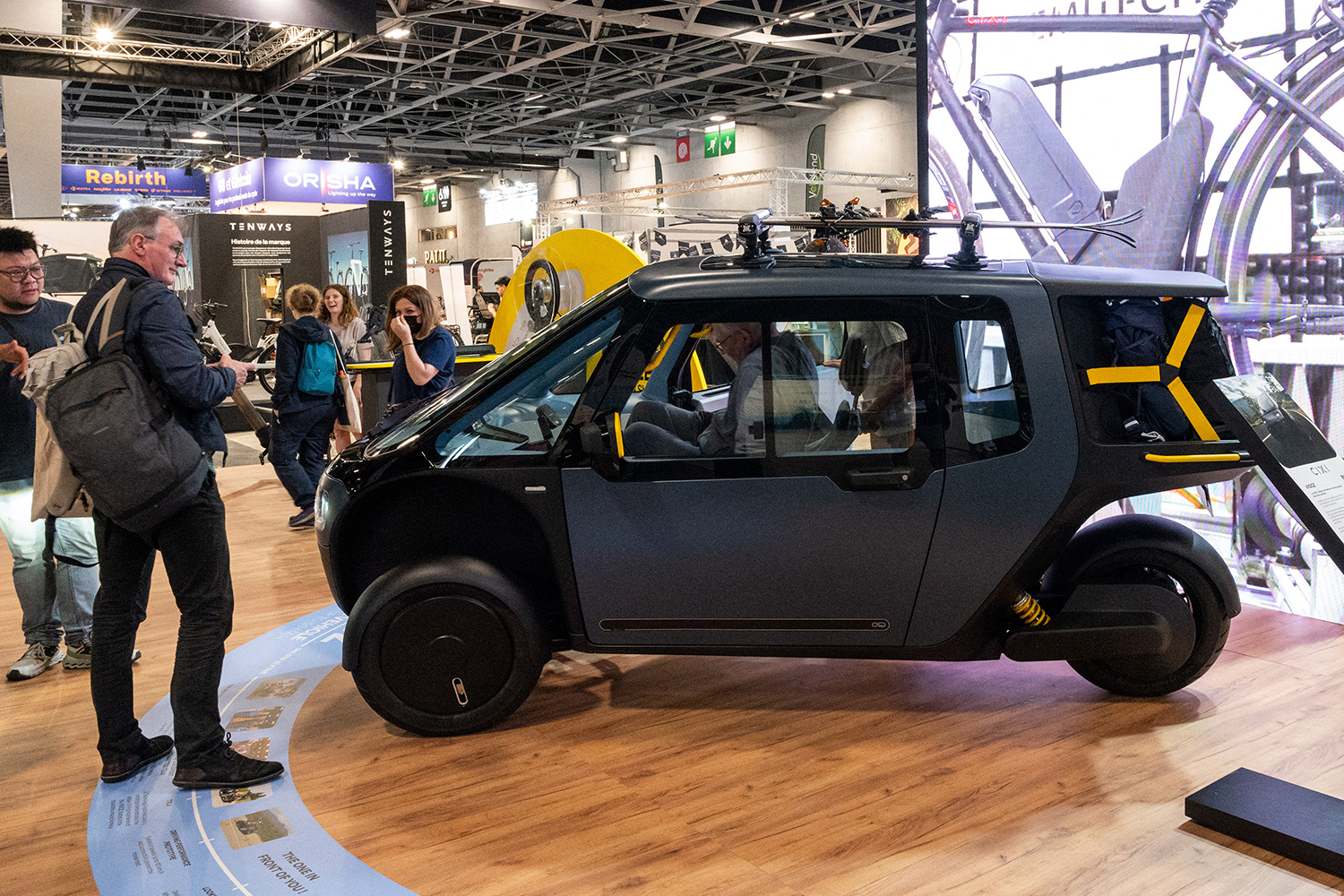 People stand in a showroom and look at the Cixi Vigoz, which is being shown from the side.