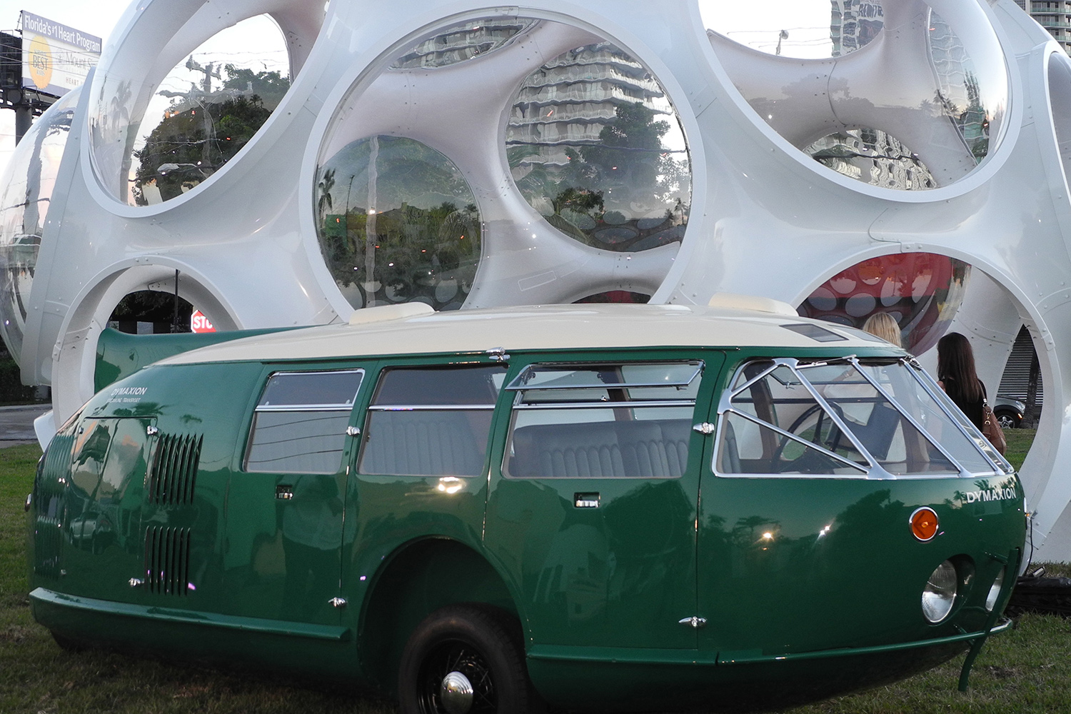 A green oblong vehicle sits in front of a futuristic, dome-shaped structure.