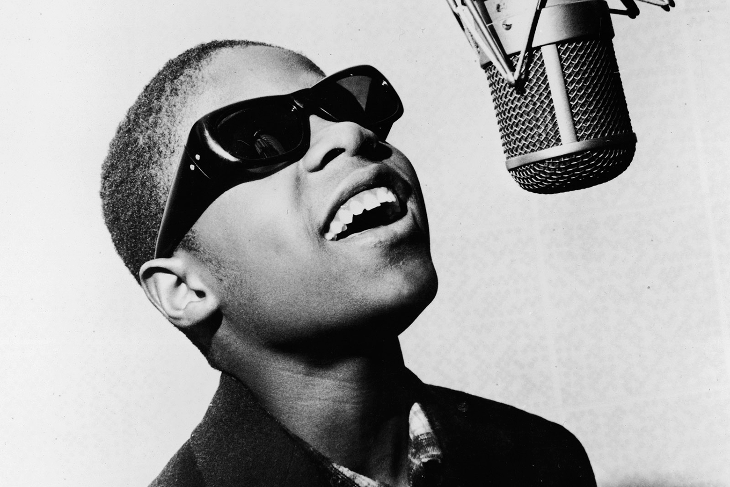 Young Stevie Wonder sings into a recording studio microphone.