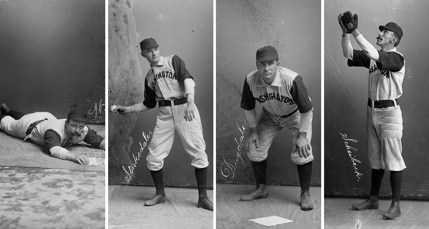 Four baseball players pose indoors wearing uniforms and striking poses as if they are playing baseball.