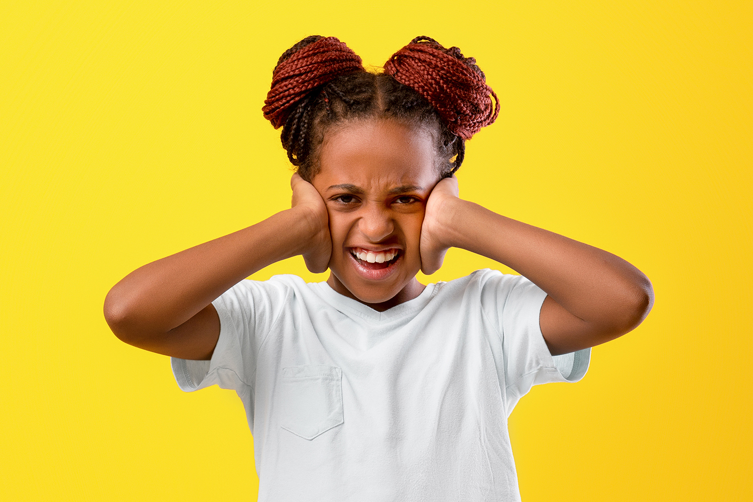 A girl makes a face while putting her hands over her ears.