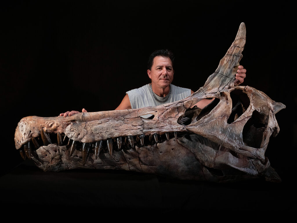 Paul Sereno and a skull cast of Spinosaurus mirabilis against a black background.