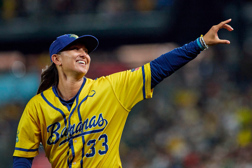 Kelsie Whitmore smiles and waves to fans while wearing a Savannah Bananas uniform.