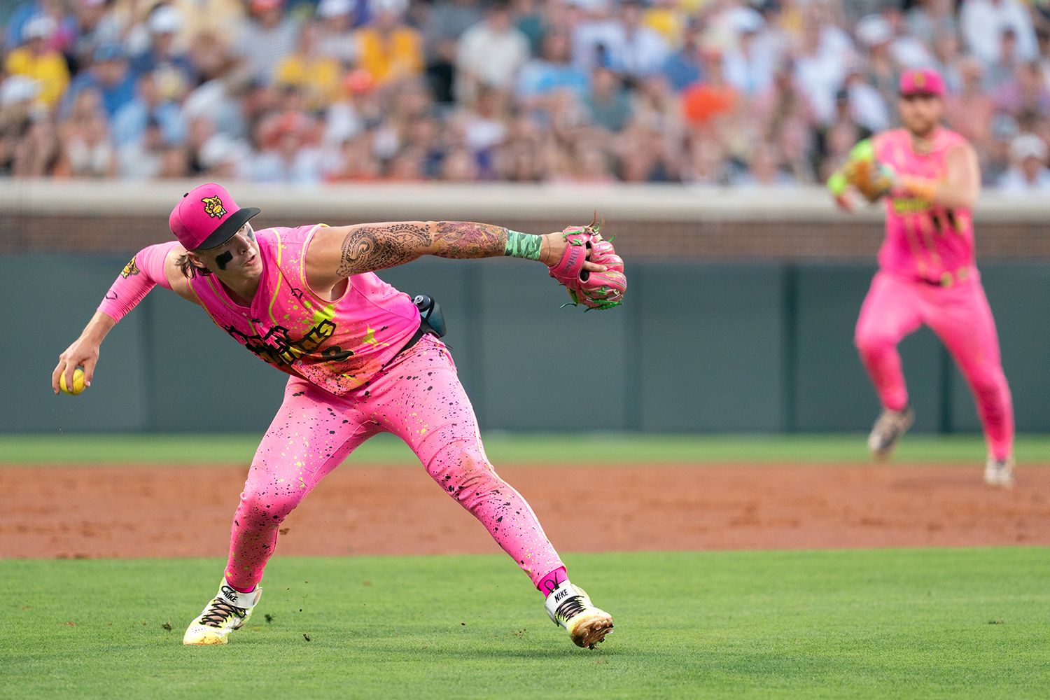 A baseball player in a pink, sparkly uniform is about to throw a baseball during a game.