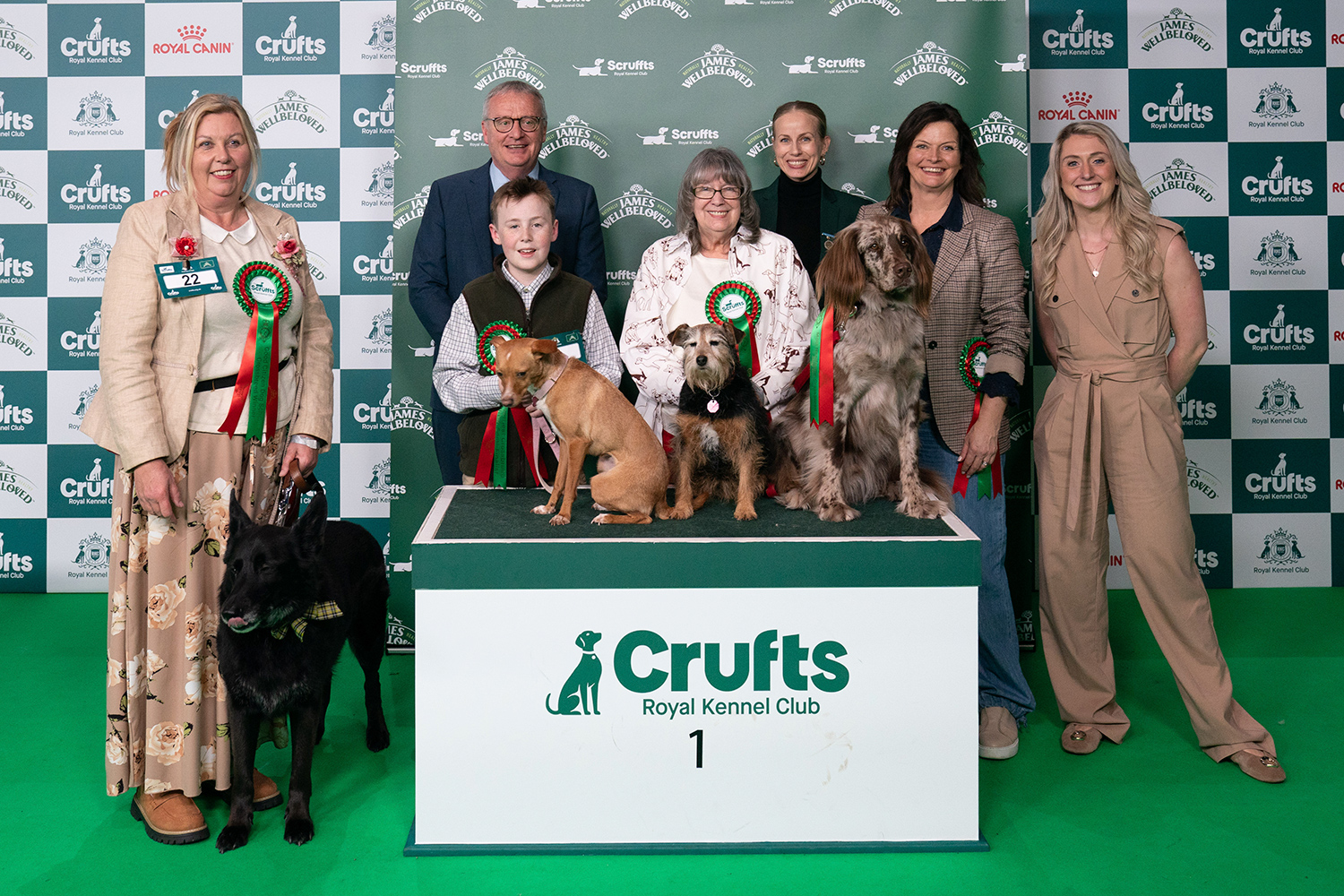 The four winning dogs pose with their owners and event officials in front of a Scruffts display.