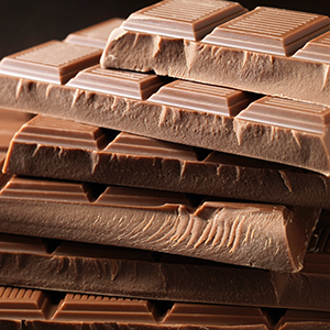 Milk chocolate bars are piled one on top of another.