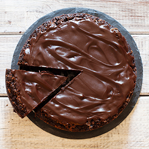 Overhead view of a slice being taken out of a chocolate cake.