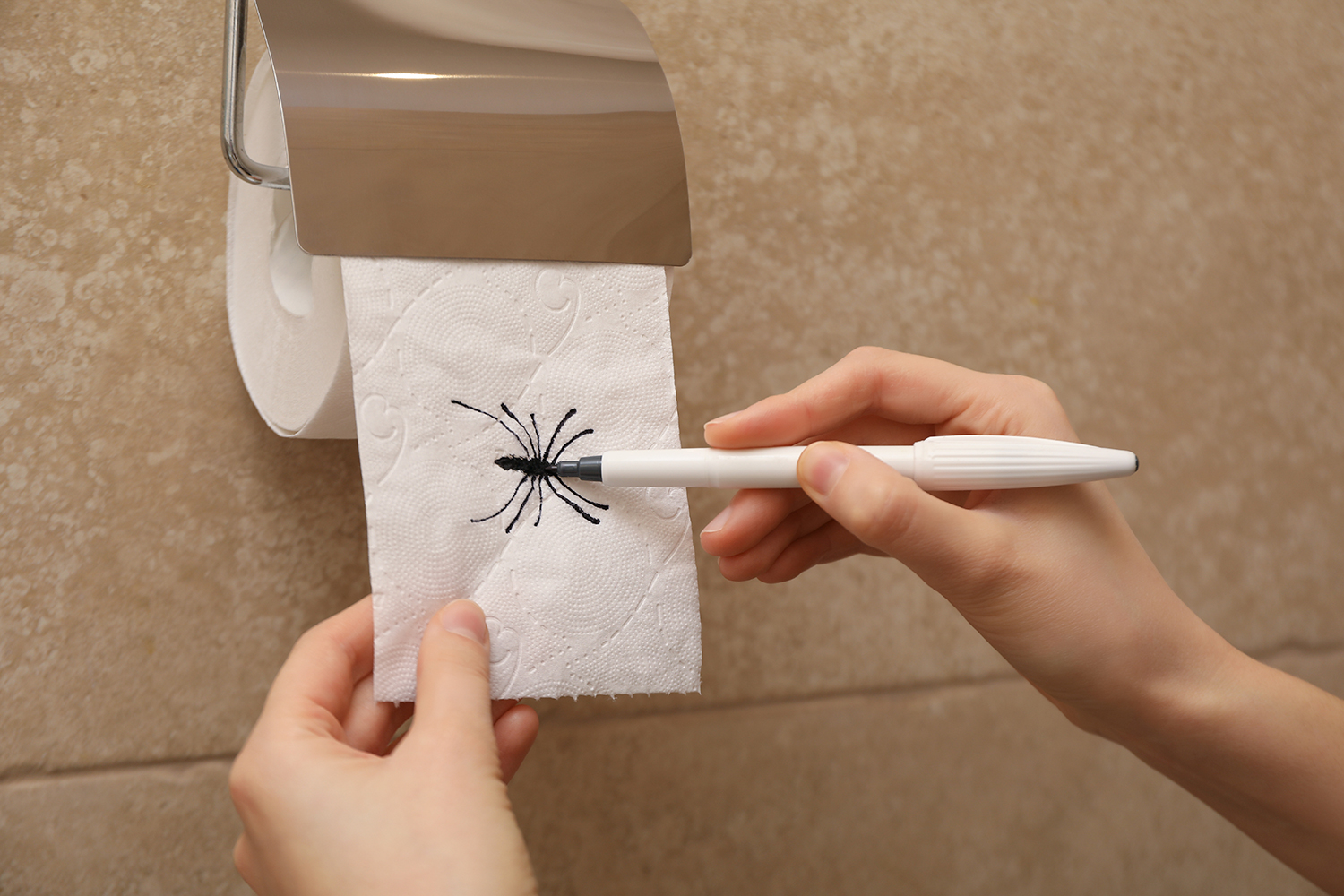 A person draws a spider on a roll of toilet paper.