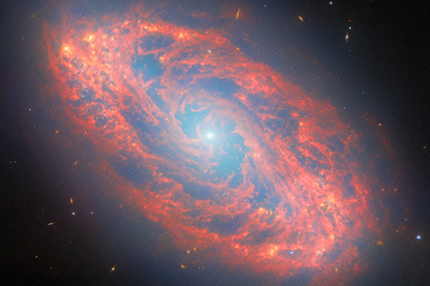 The NGC 5134 spiral galaxy appears to be made up of stars and red gases against the black background of the universe.
