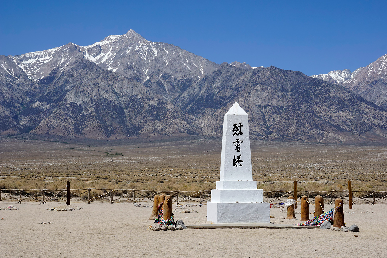 A white obelisk with Japanese characters is in front of a mountainous background.