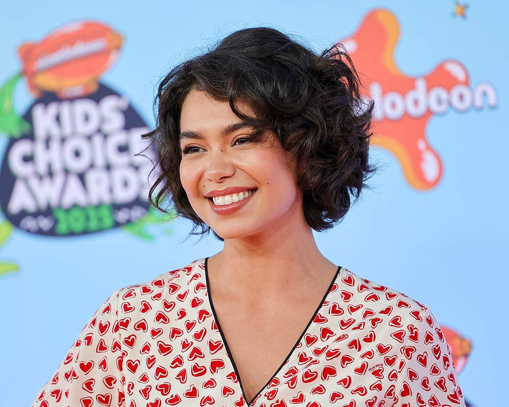 Auli’i Cravalho smiles in front of a background that shows she is at the Nickelodeon Kids’ Choice Awards.