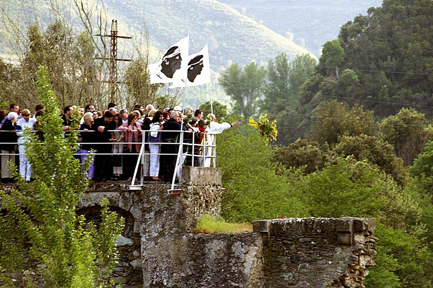 People stand on a stone platform with a railing.