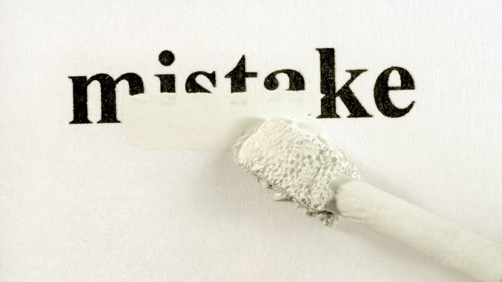 The word "mistake" typed on a piece of paper, partially covered by white correction fluid