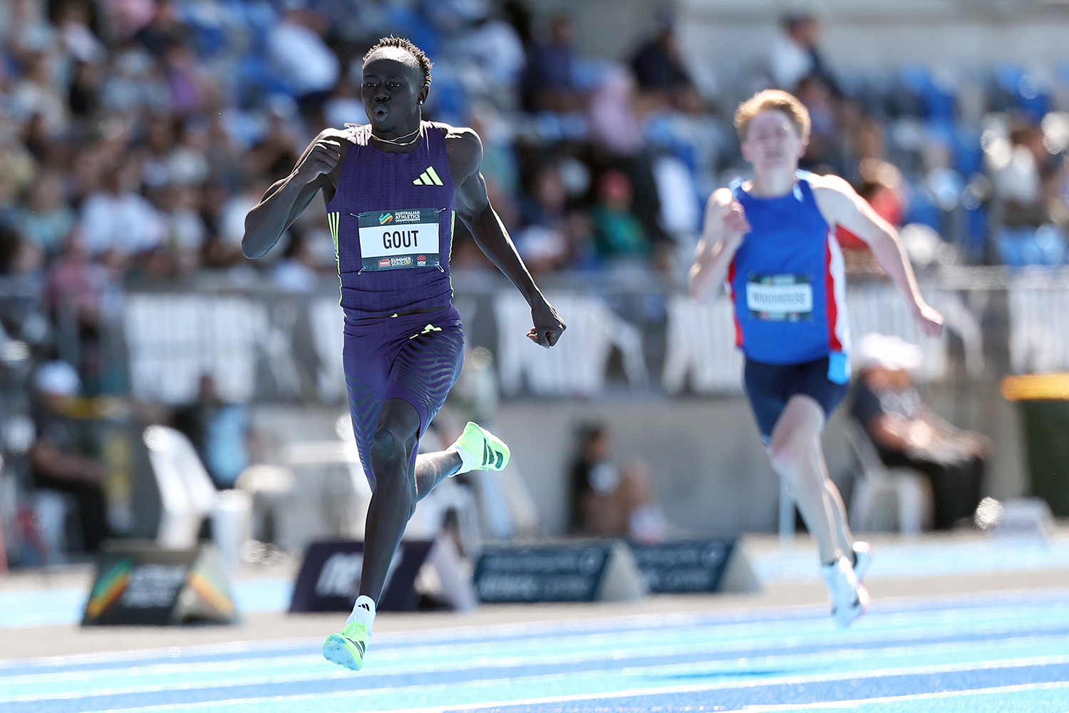 Gout Gout runs on a track with another runner close behind him and a crowd in the background.