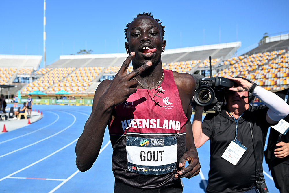 Gout Gout makes a victory sign as a photographer stands behind him and takes a photo.