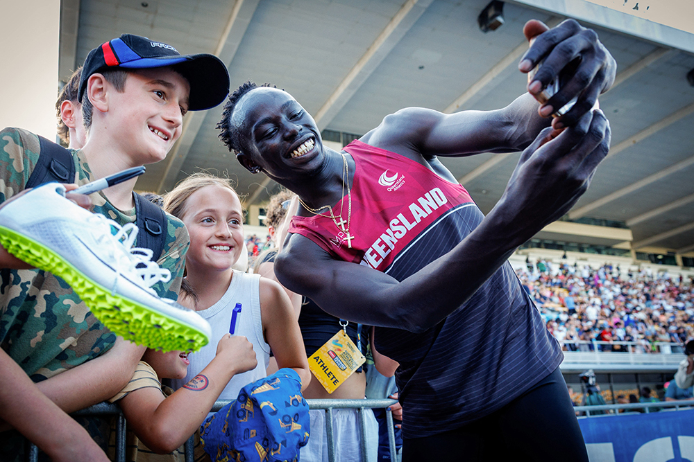 Gout Gout smiles and holds a camera to take a selfie with three young fans.
