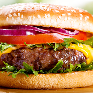 A hamburger with cheese, lettuce, tomato, and onion.