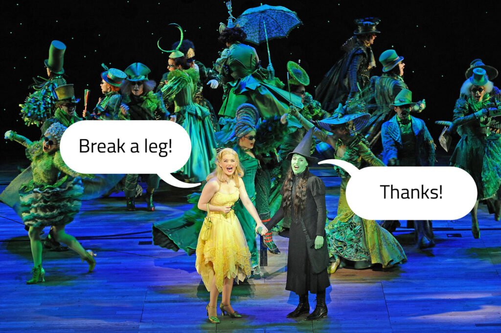 With several cast members on stage to perform Wicked, the actor playing Glinda says “Break a leg” and the actor playing Elphaba says “Thanks.”