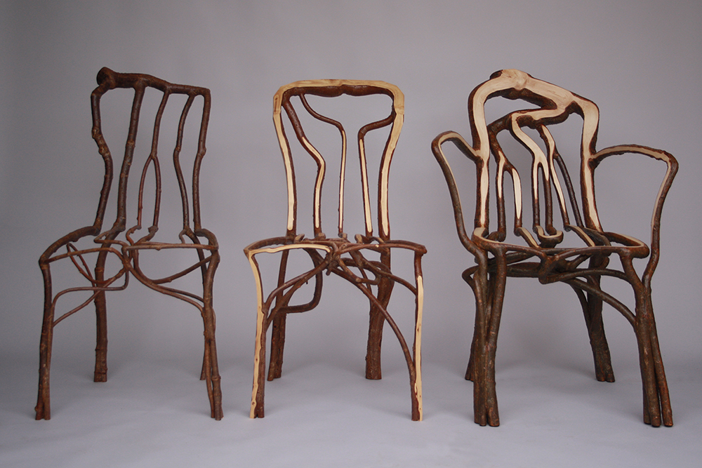 Three chairs shaped by tree branches stand inside a studio.