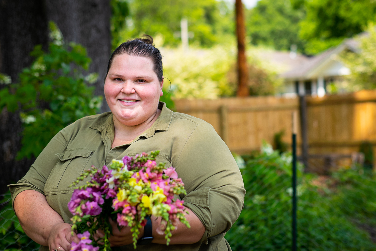 Marisa Mender-Franklin poses in a yard with a bouquet of flowers.