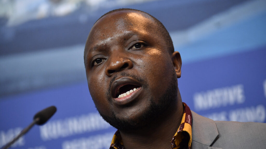 A closeup of William Kamkwamba speaking into a microphone.