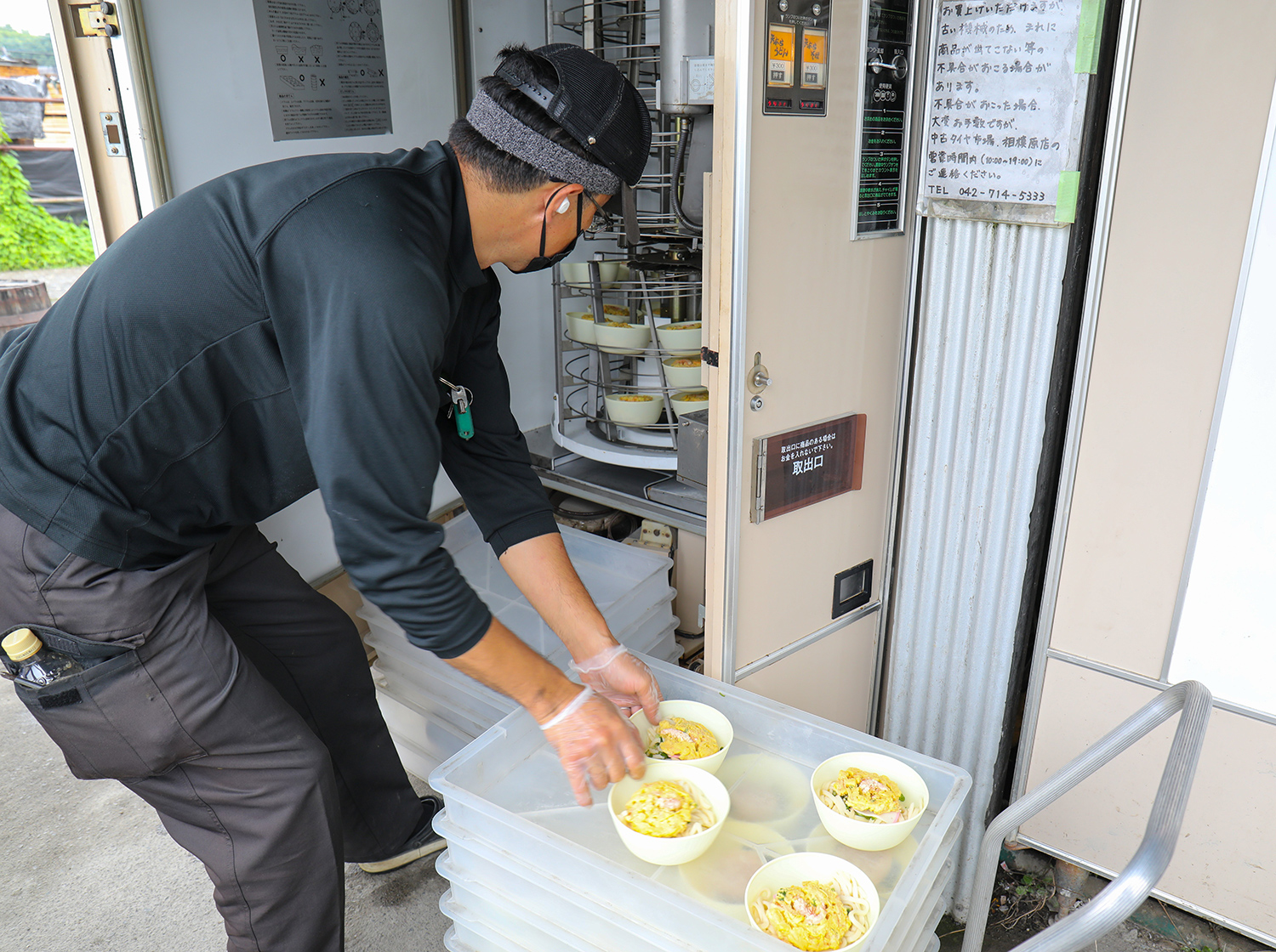 A man loads some bowls of noodle meals into a vending machine.