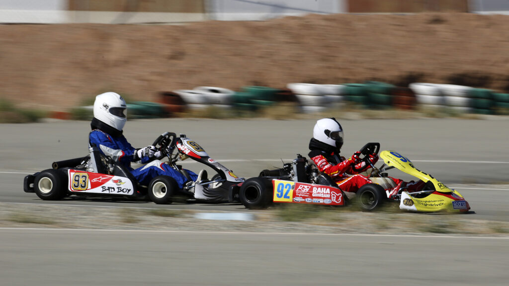 Two people in go karts race each other on a track.