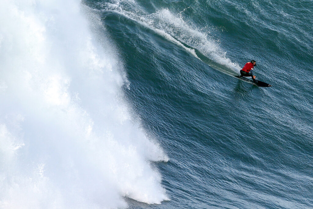 Maya Gabeira rides a massive wave that is breaking.