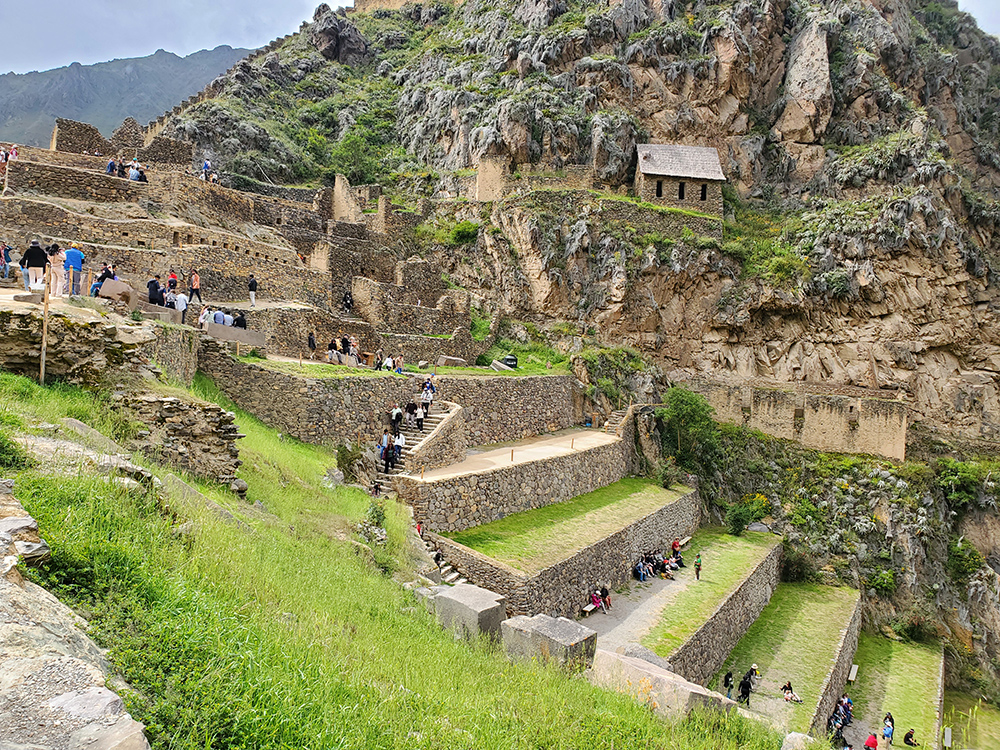 People walk on steps among Inca ruins in the mountains.