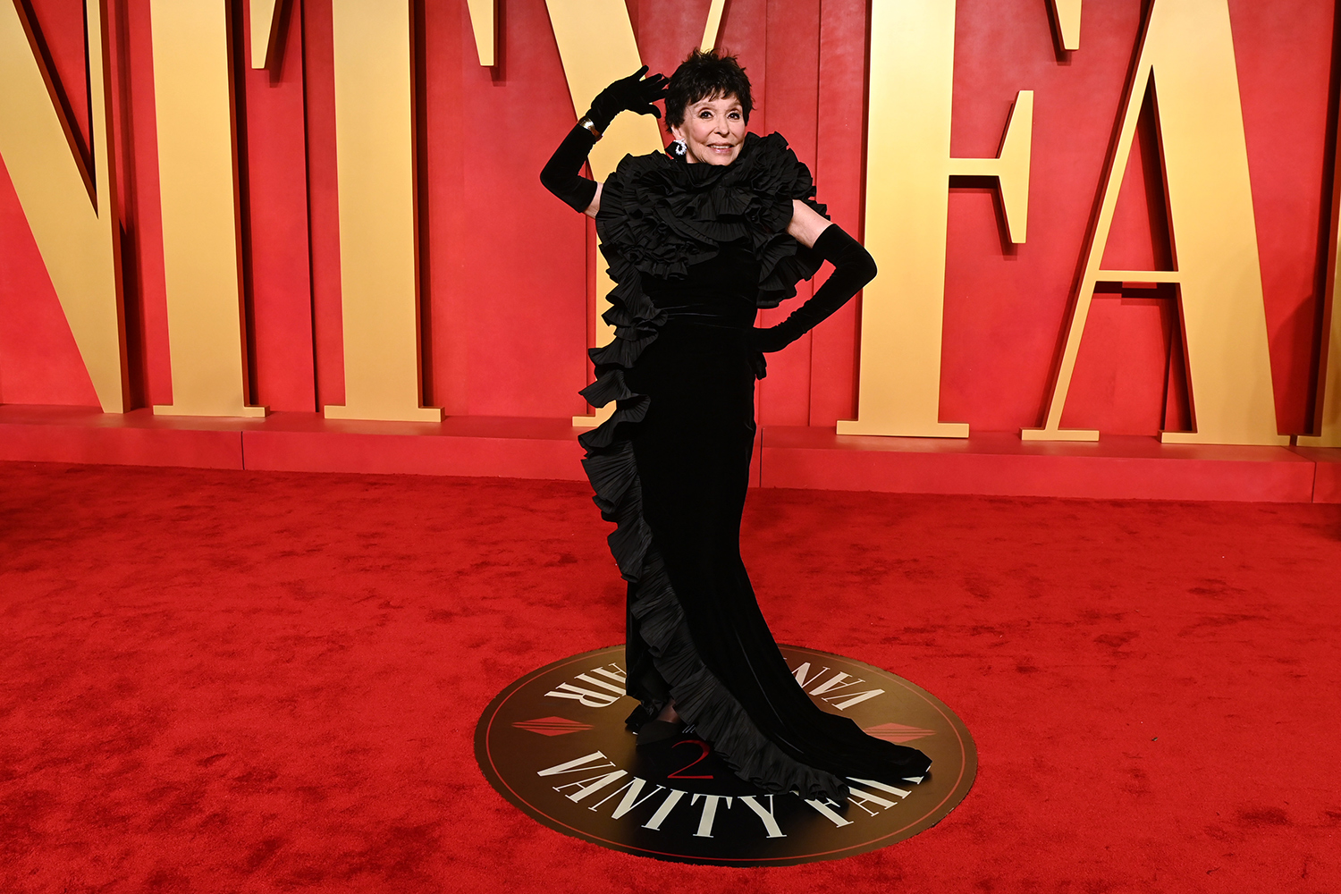 Rita Moreno poses and smiles on a red carpet for a Vanity Fair event.