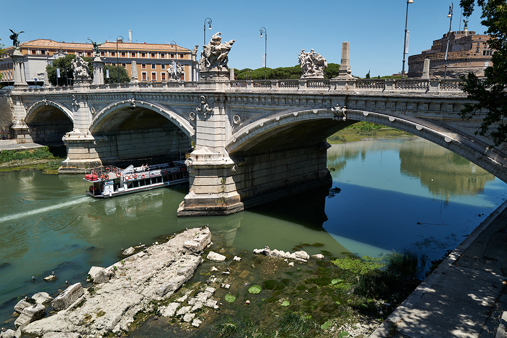 The ruins of an ancient Roman bridge are shown emerging from a river and near the Vittorio Emanuele II bridge in Rome.