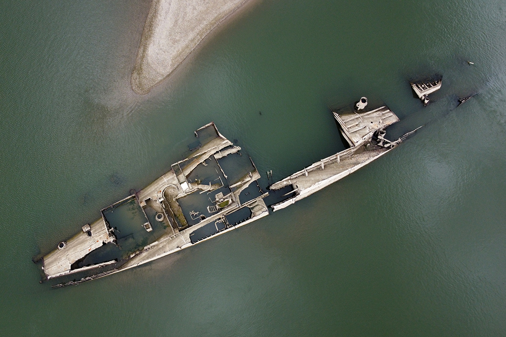 The wreckage of a German World War II ship is exposed in low water next to a sandbar.