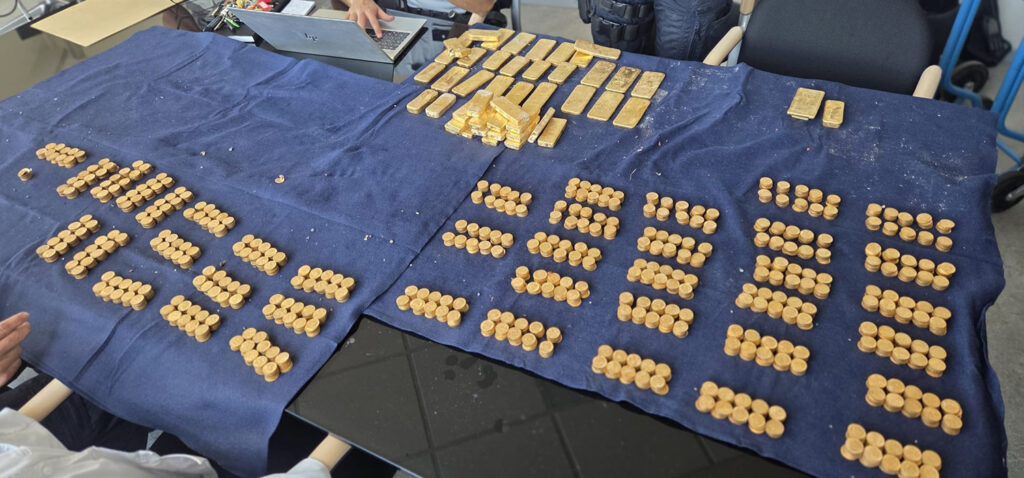 Gold coins and bars are laid out on a table.