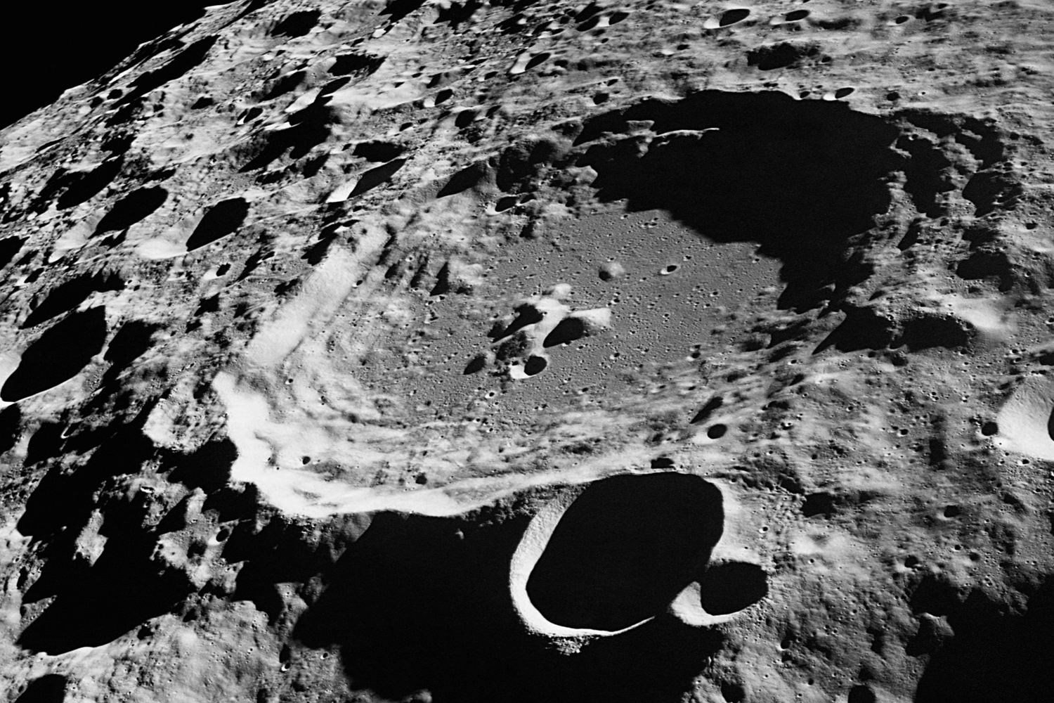 One large crater is surrounded by several small craters on the surface of the Moon.