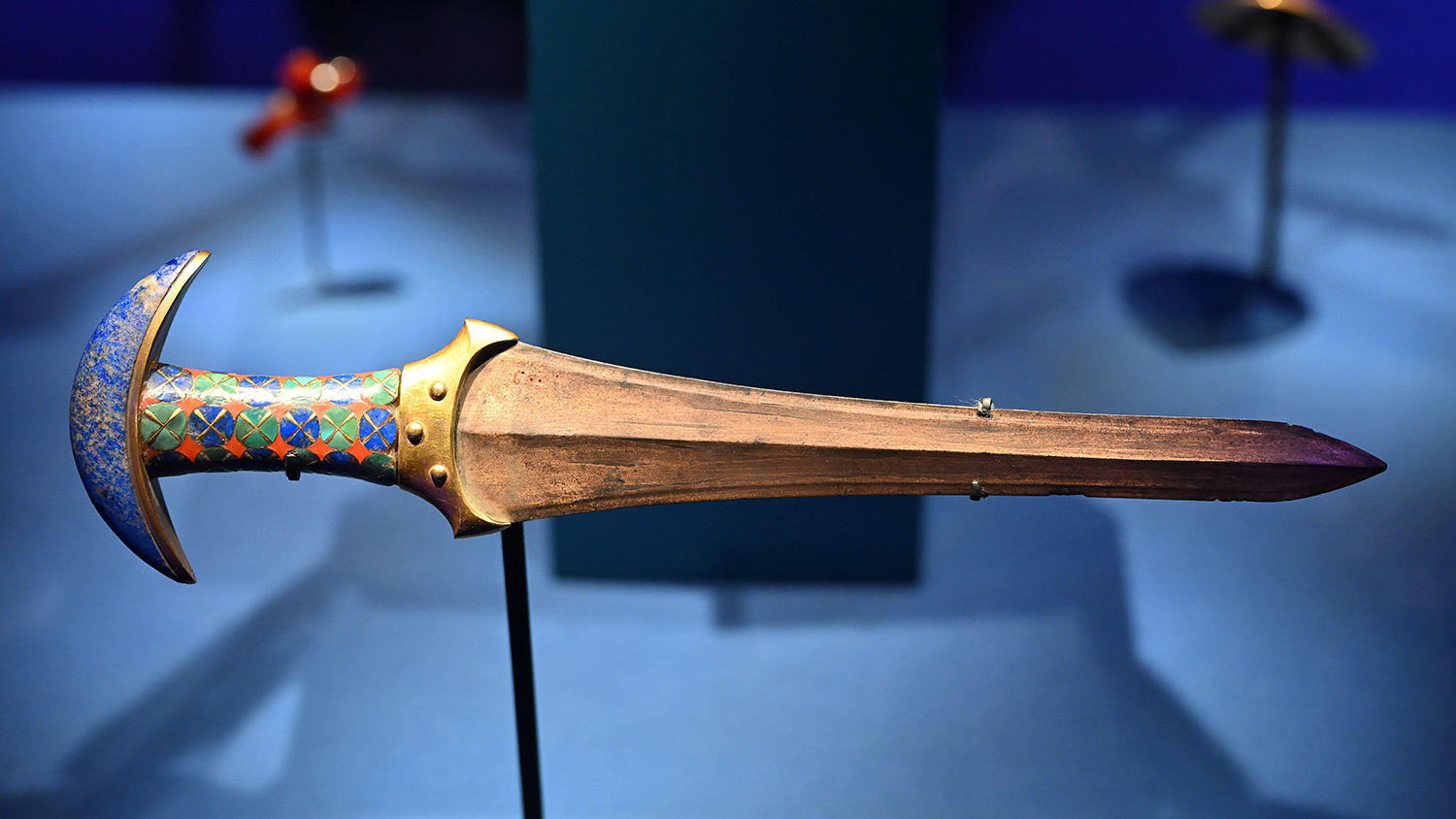 A dagger has a colorful geometric design on its handle.