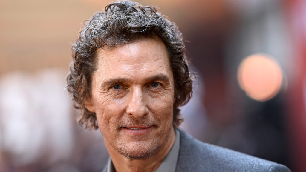 Closeup of Matthew McConaughey smiling at the camera while wearing a shirt and blazer.