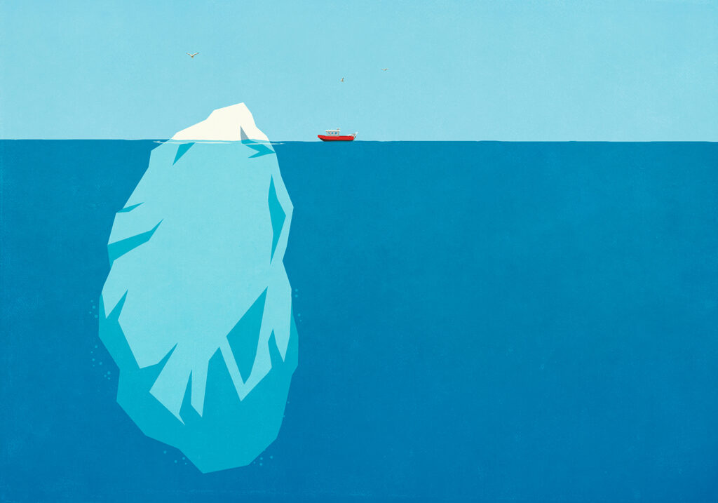 A boat travels toward an iceberg, most of which is visible under the surface of the water.