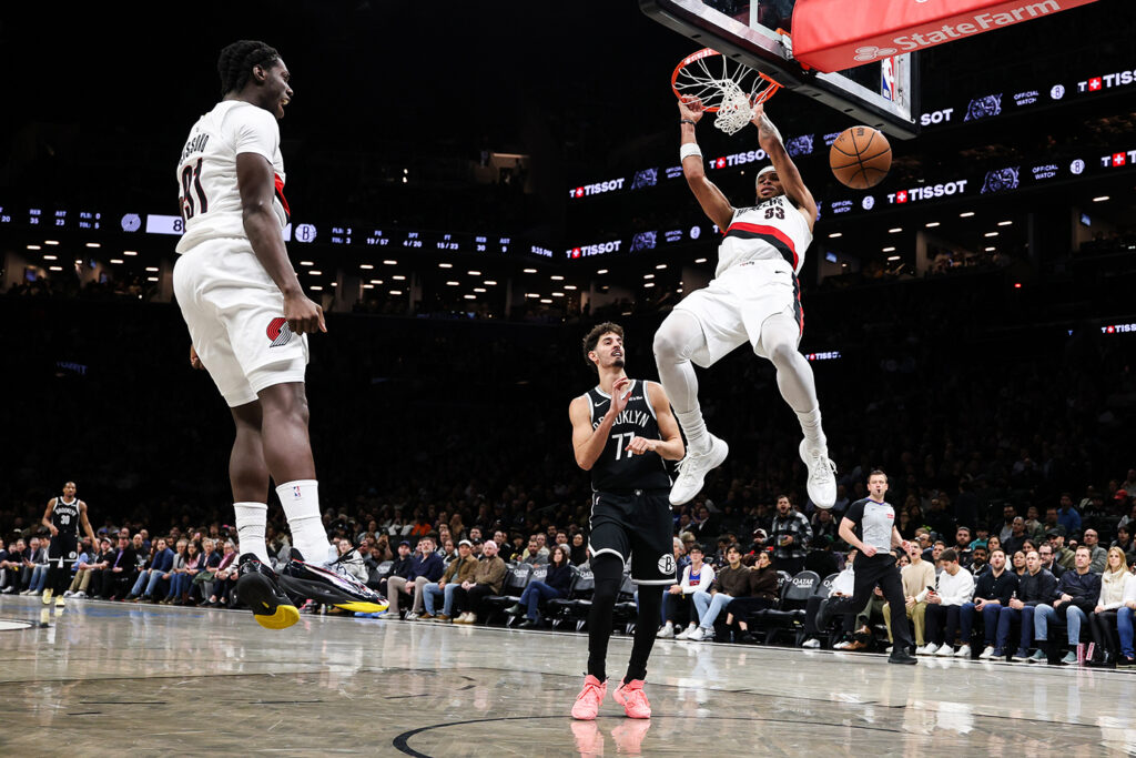 Toumani Camara dunks a basketball during a game as other players watch.