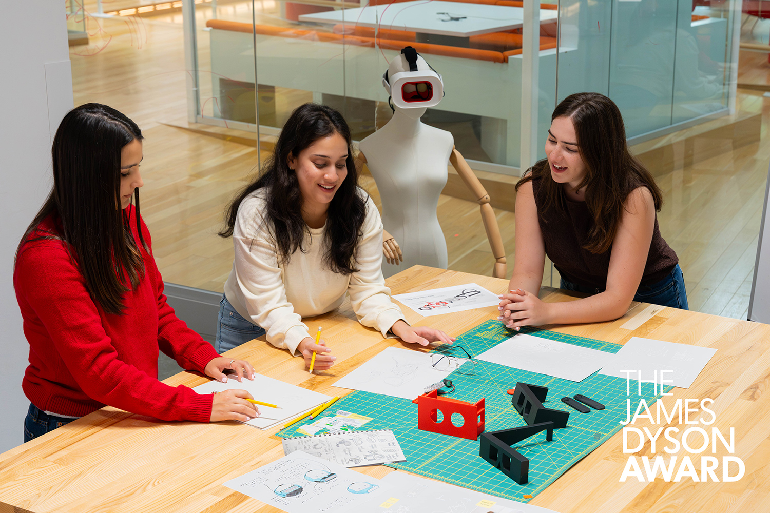 The Rumble Rims inventors sit at a table with paper, pencils, designs, and prototypes.