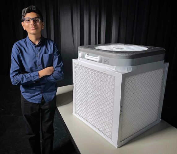 Teenage boy standing next to a Corsi-Rosenthal box