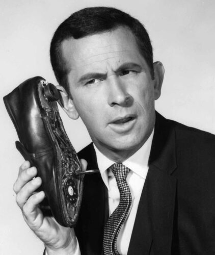 Black and white photo of Don Adams from Get Smart holding a shoe phone